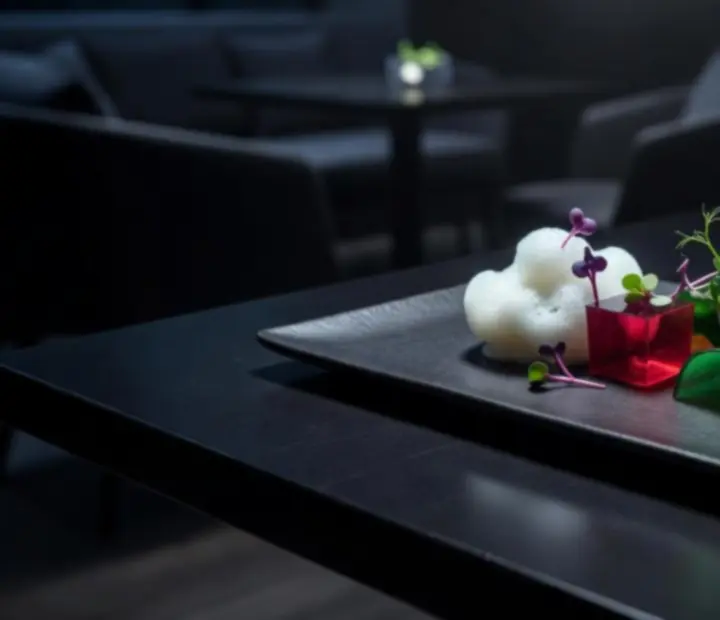 Molecular gastronomy dish presented with modern plating in a dark lounge